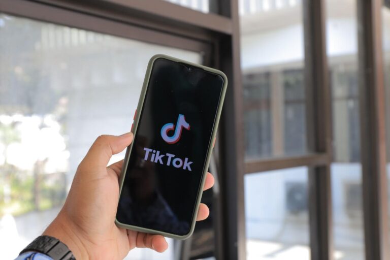 Seseorang sedang memegang smartphone untuk mengakses aplikasi seluler sebagai ilustrasi panduan ekosistem koin tiktok